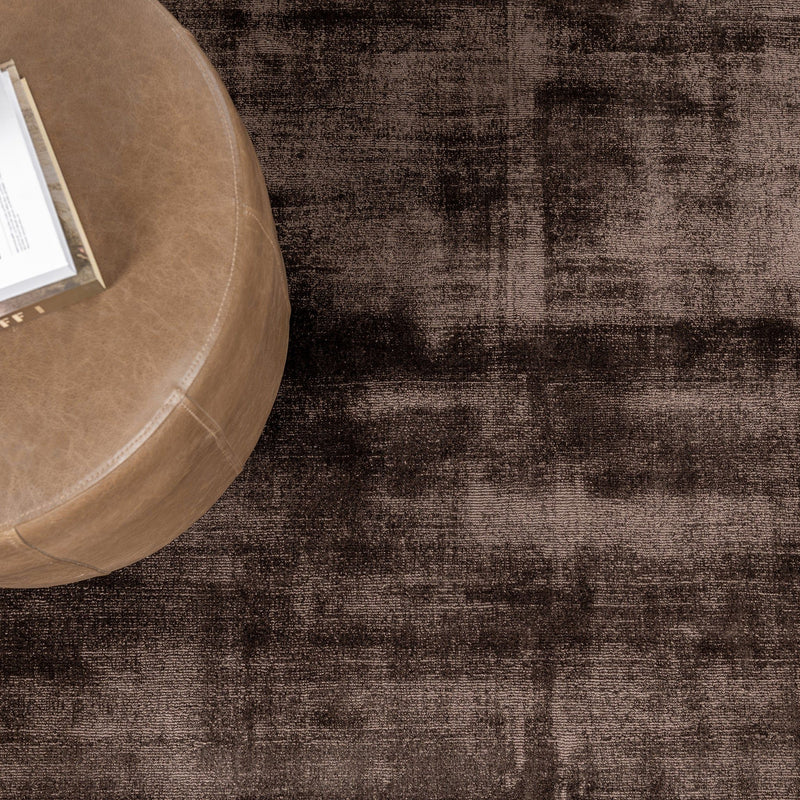 Dark brown distressed area rug with worn, mottled look and flat, dense pile.