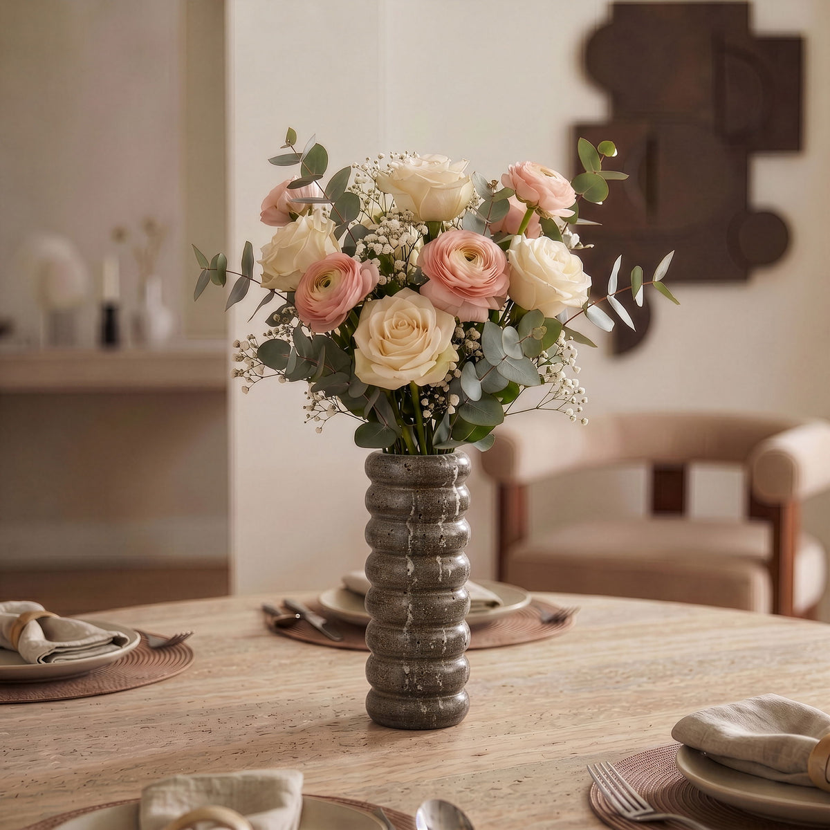 Gray travertine vase holding a bouquet of roses and baby’s breath