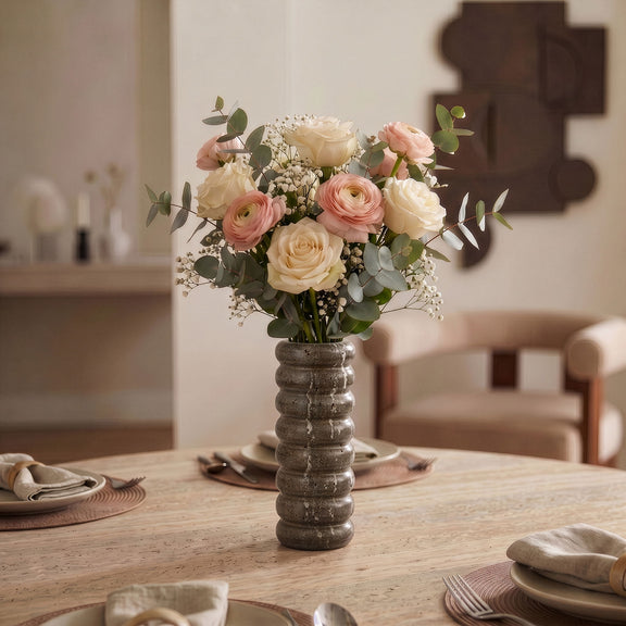 Gray travertine vase holding a bouquet of roses and baby’s breath