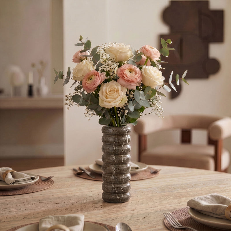 Gray travertine vase holding a bouquet of roses and baby’s breath