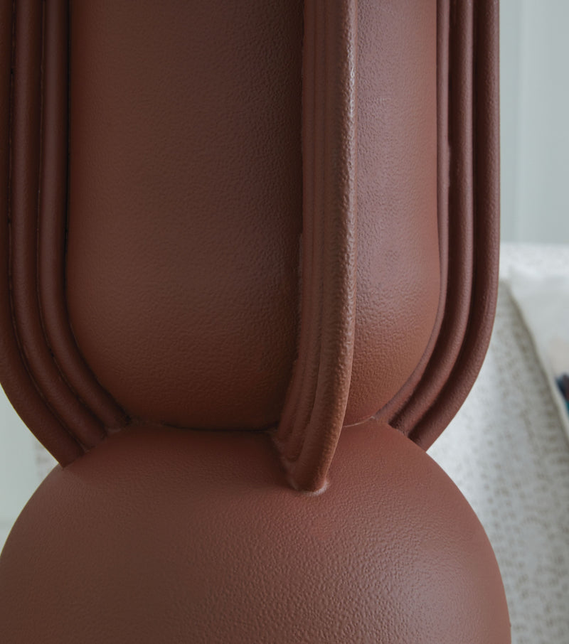Close-up of brick red ribbed metal lamp body with white drum shade