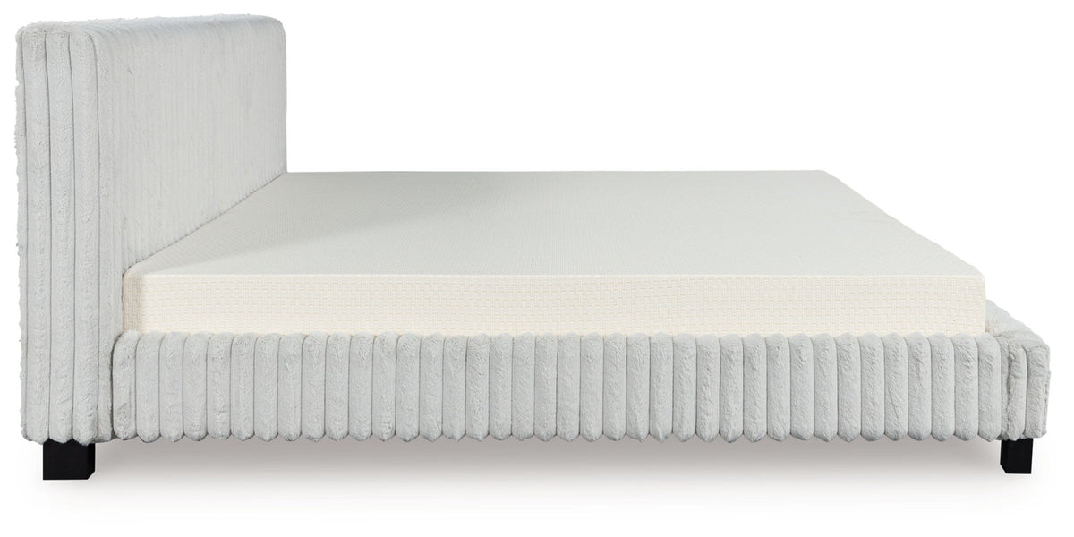 White upholstered bed frame with ribbed vertical sides, solid headboard, and mattress.