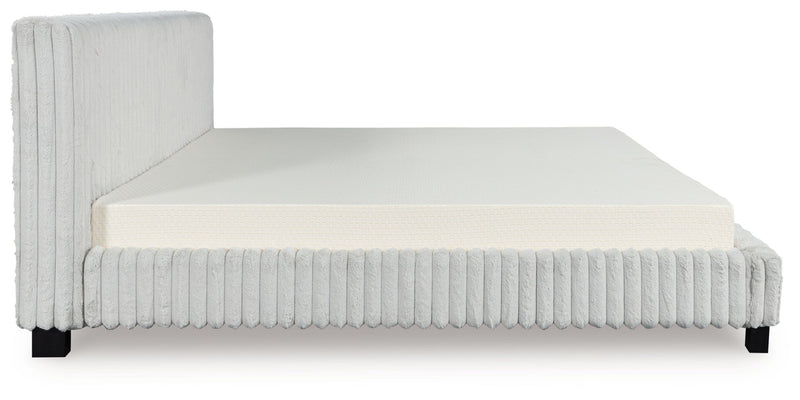 White upholstered bed frame with ribbed vertical sides, solid headboard, and mattress.