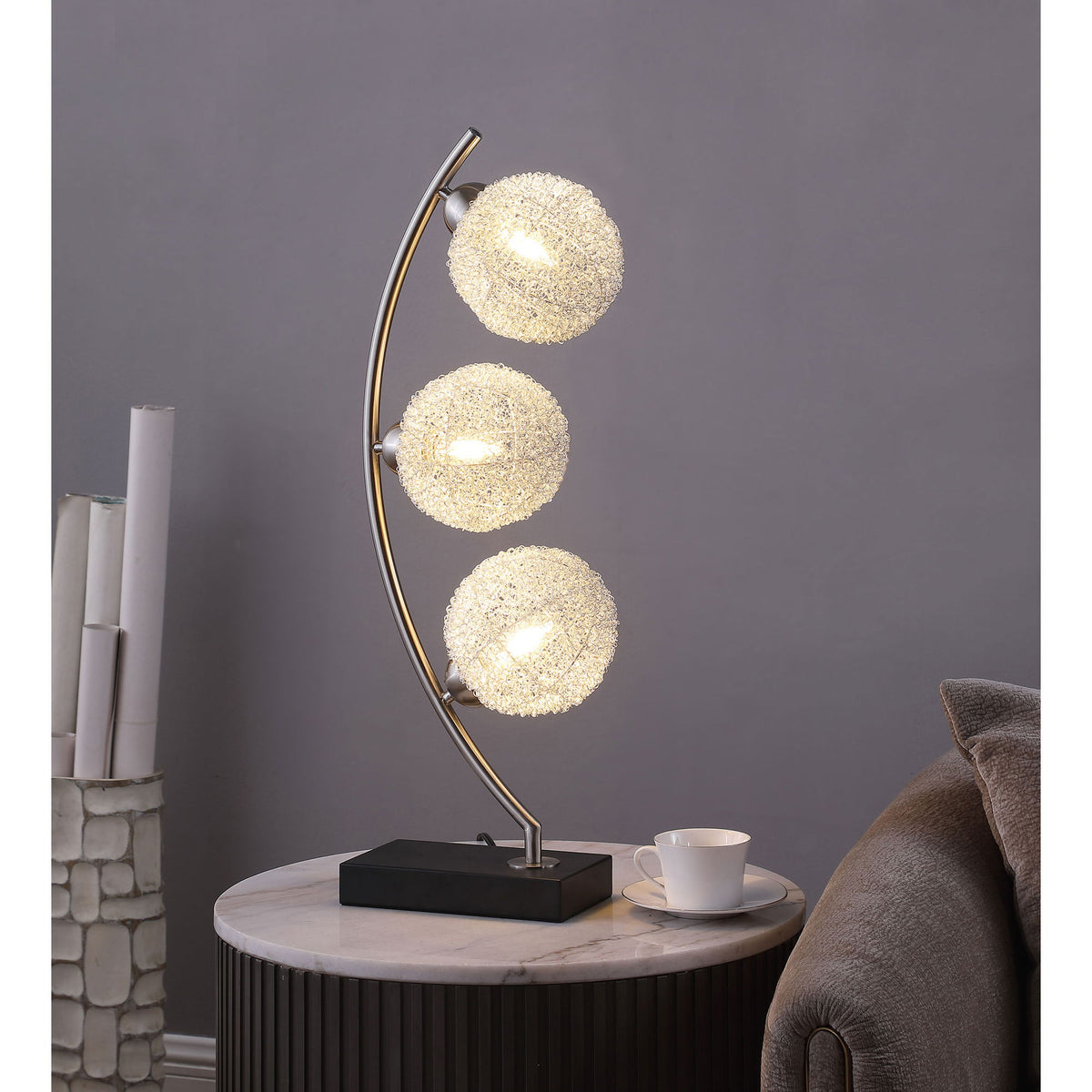 Black base table lamp with curved stand and three lit gold LED globe bulbs