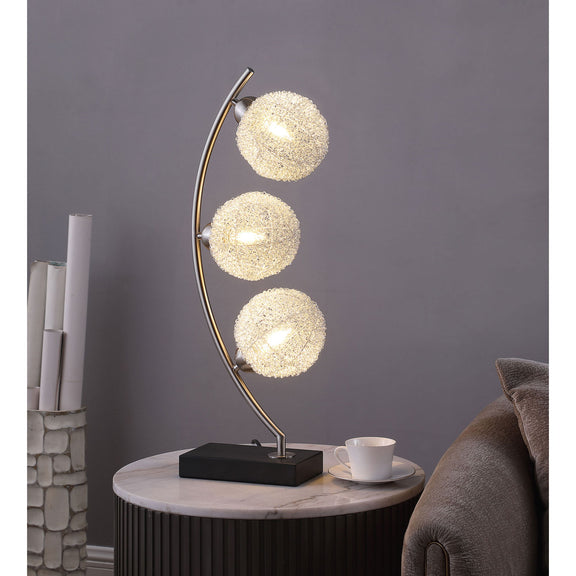 Black base table lamp with curved stand and three lit gold LED globe bulbs