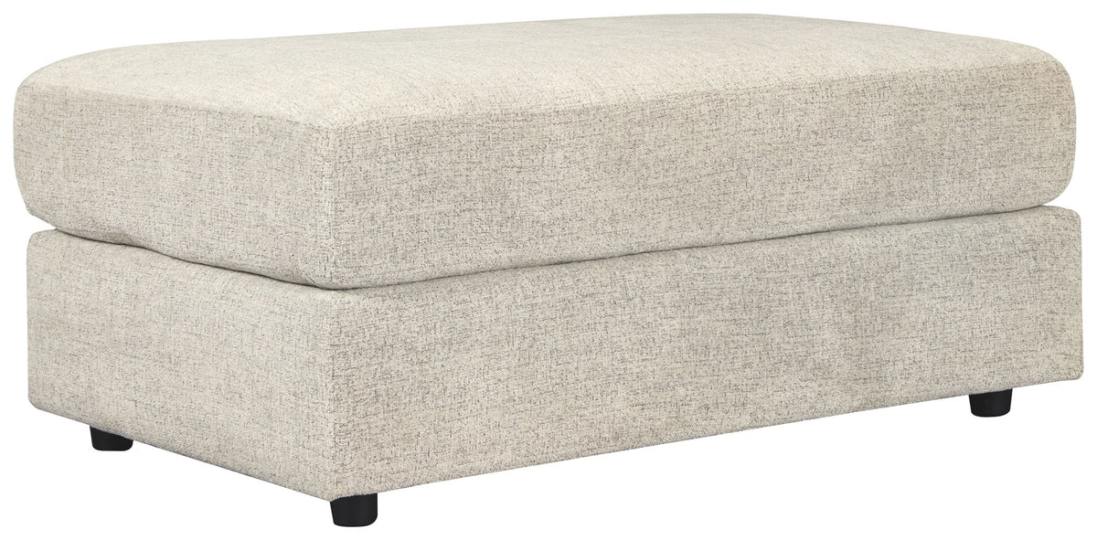 Stone-colored upholstered oversized ottoman with rounded top and black legs