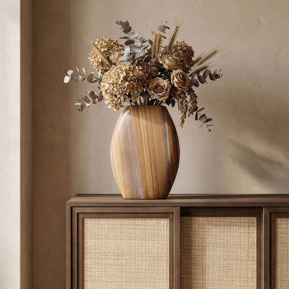 Sandstone vase in sand-beige holding a dried flower arrangement.