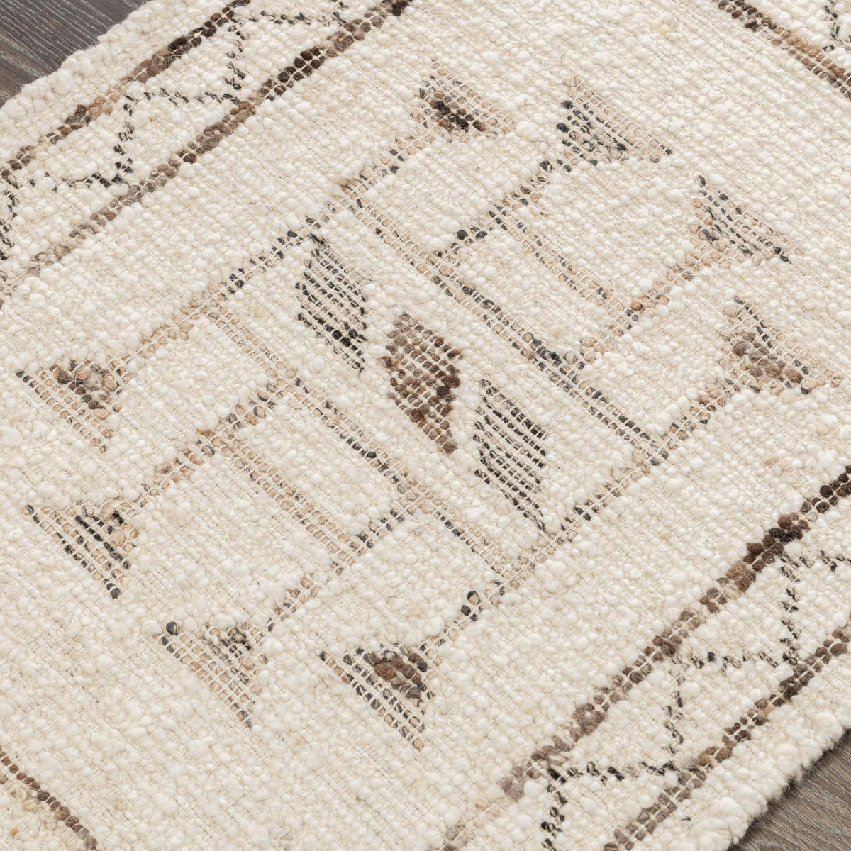 Close-up of ivory rug weave with dark geometric lines and small scattered motifs