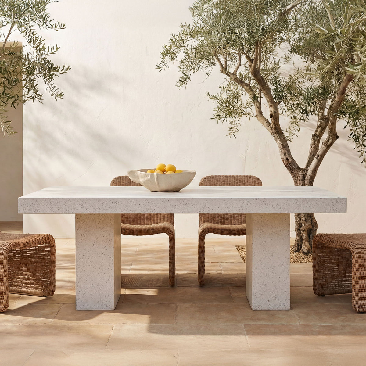 Outdoor dining table with light terrazzo top and wide pedestal base, set for dining