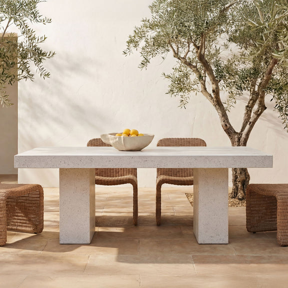 Outdoor dining table with light terrazzo top and wide pedestal base, set for dining