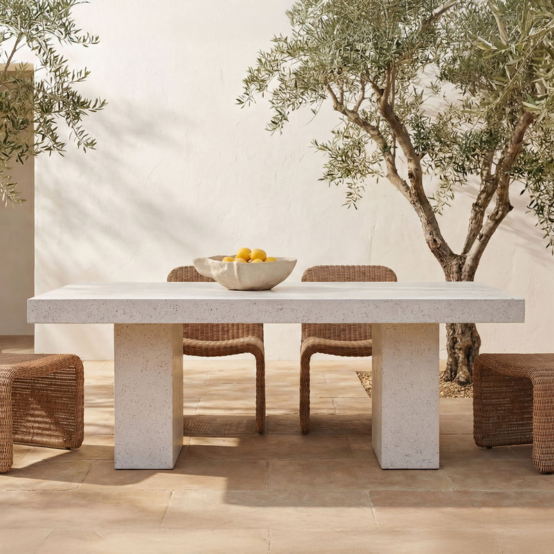 Outdoor dining table with light terrazzo top and wide pedestal base, set for dining