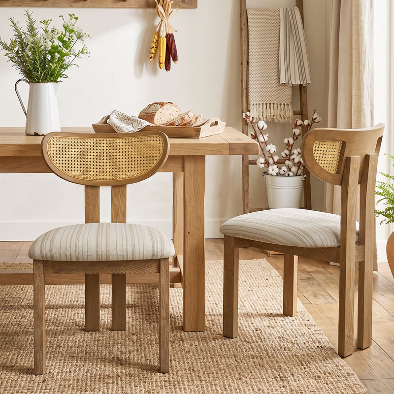Set of two striped upholstered dining chairs with light brown wood frames and woven rattan backs