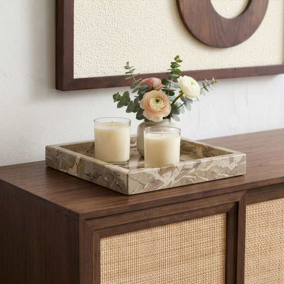 Stone tray with two candles and flowers on a wooden sideboard