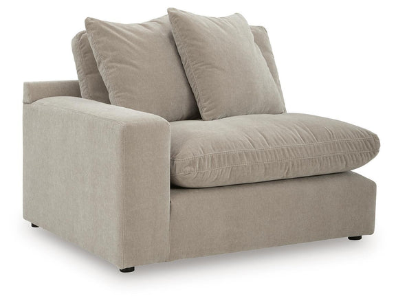 Light beige sectional chaise with two throw pillows and padded armrest.
