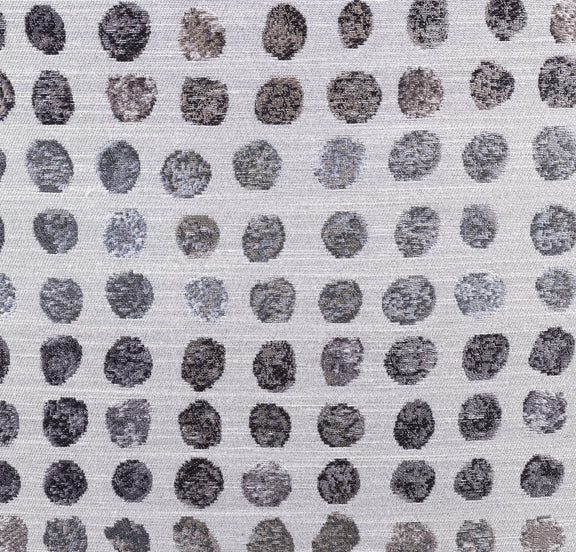Close-up of ink-dot fabric upholstery on an ottoman, small dark circle pattern