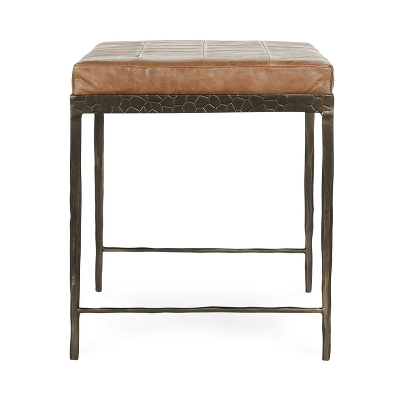 Brown leather bench with textured front skirt, padded seat, and dark legs