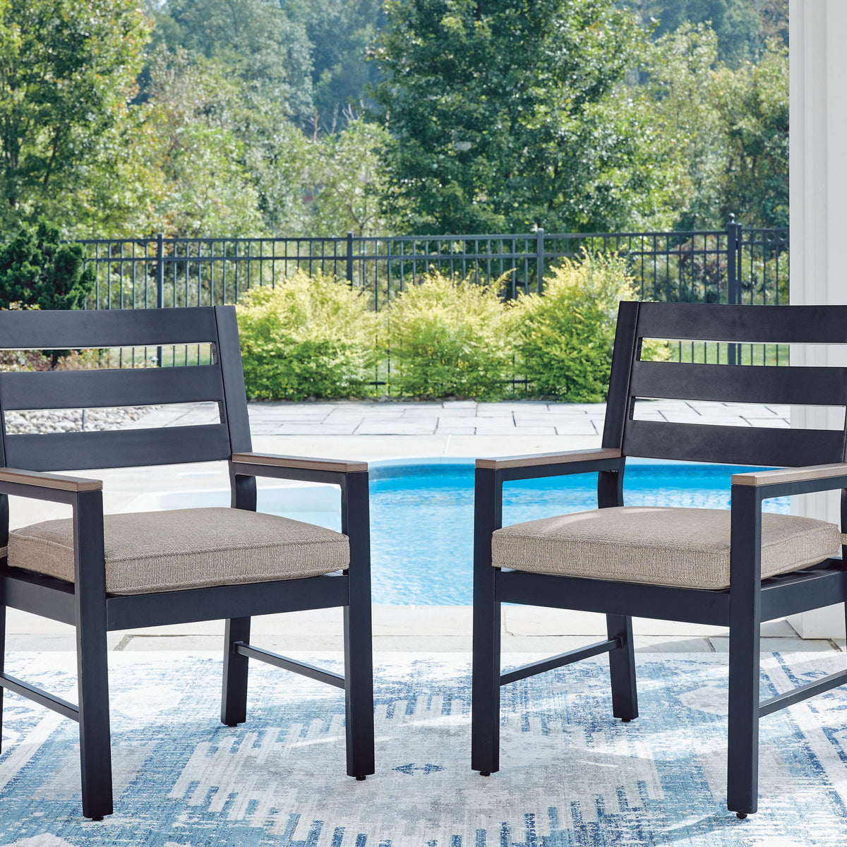 Two blue arm chairs with light gray cushions and slatted backs for outdoor seating