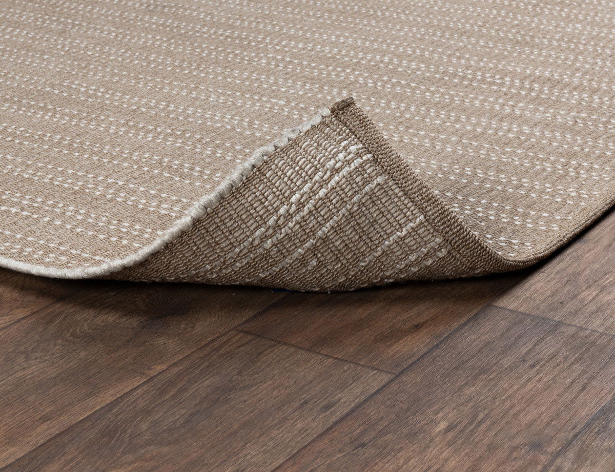 Sand indoor/outdoor rug corner detail showing flat weave and textured underside.