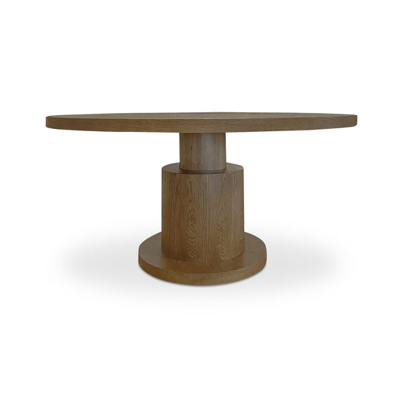 Brown wooden dining table with a round top and sculptural cylindrical pedestal base