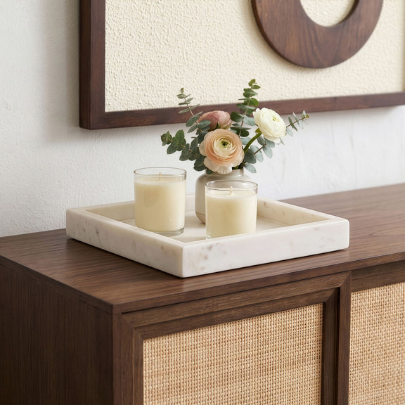 White marble tray with two candles and flower arrangement on a wooden table