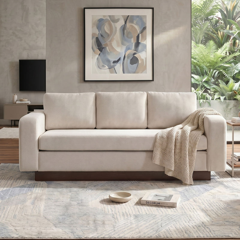 Cream 3-seater sofa with three back cushions and draped throw blanket