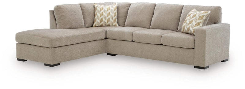 Beige corner chaise sectional sofa with smooth back cushions and two patterned throw pillows.