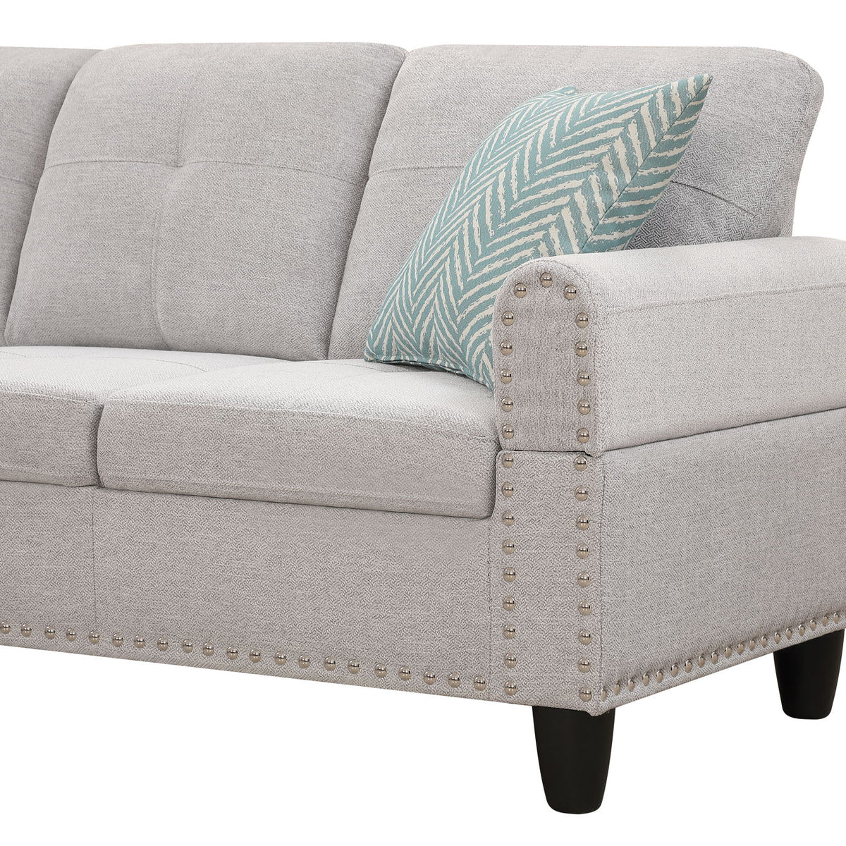 Light gray sofa arm with nailhead trim and blue patterned throw pillow