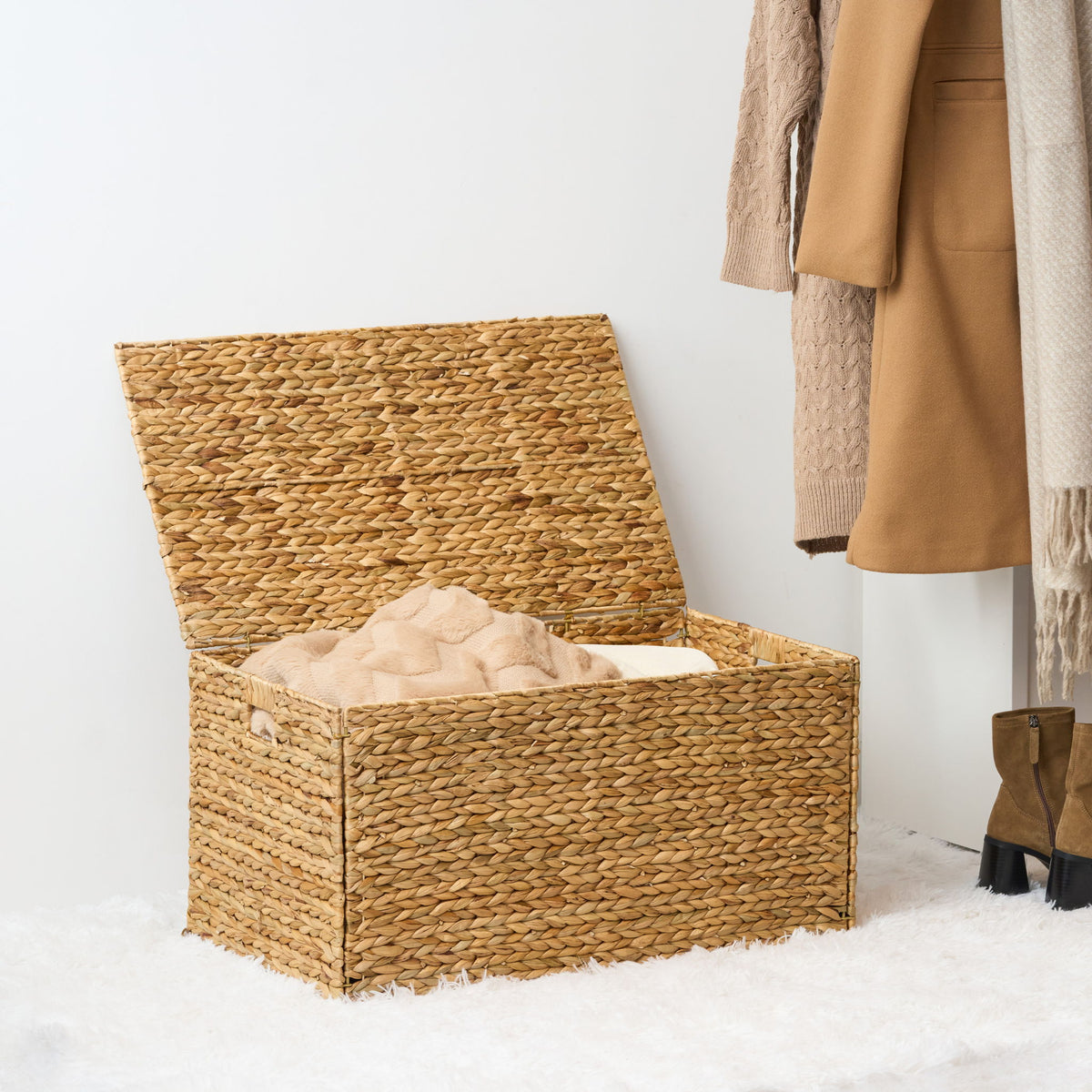 Open woven trunk holding blankets, with its hinged lid raised