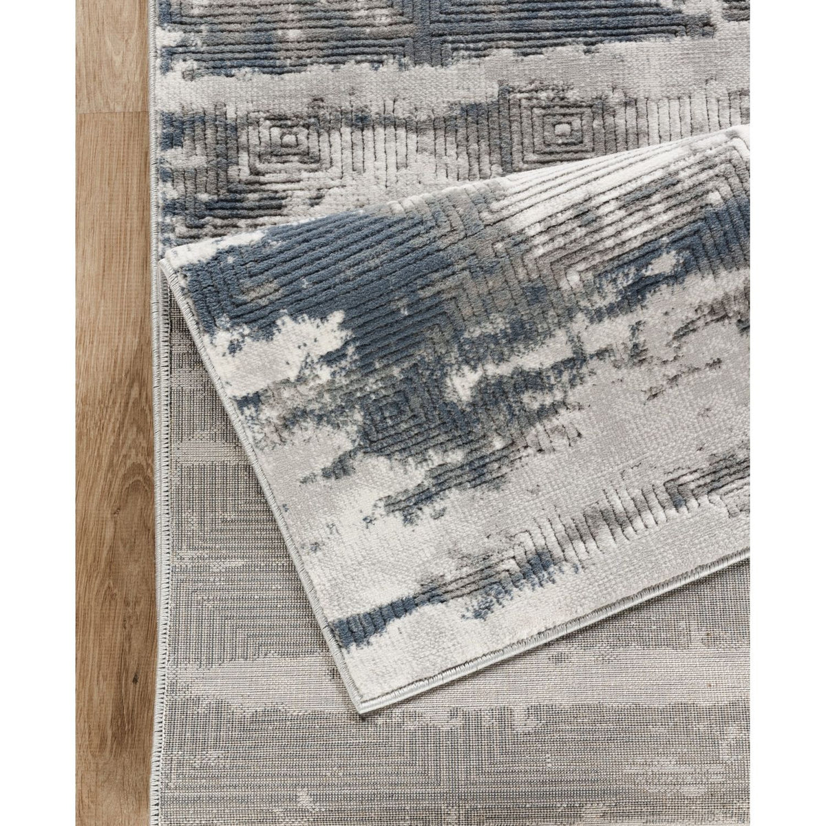 Gray and blue area rug corner detail with geometric motif and textured weave