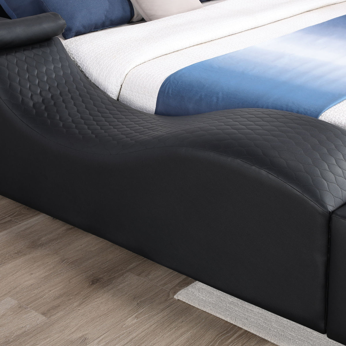 Black upholstered massage bed with quilted padding and curved side panel