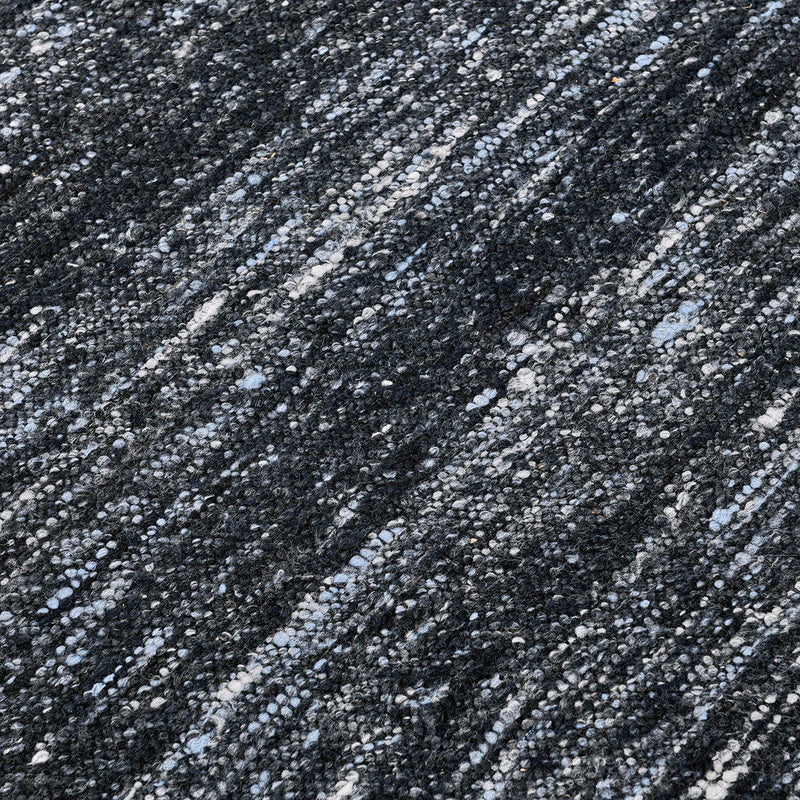 Close-up of dark blue area rug showing speckled texture and woven stripe pattern.