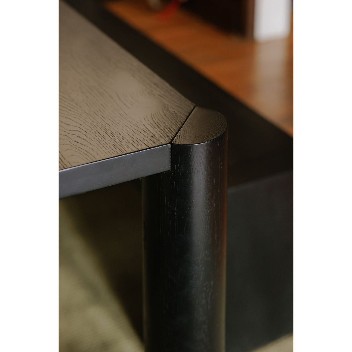 Black oak corner detail of small dining table with rounded leg post and edge
