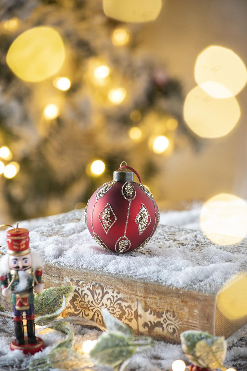 Red and gold decorative hanging Christmas ball ornament on snow with nutcracker figurine