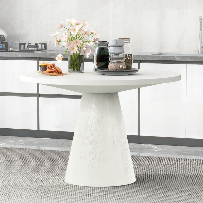 White round pedestal dining table with a smooth, wide top
