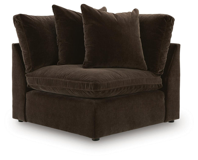 Dark brown sectional chaise with three throw pillows and tufted seat cushion.