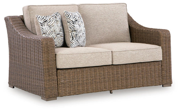 Wicker loveseat with beige seat cushions and two patterned throw pillows
