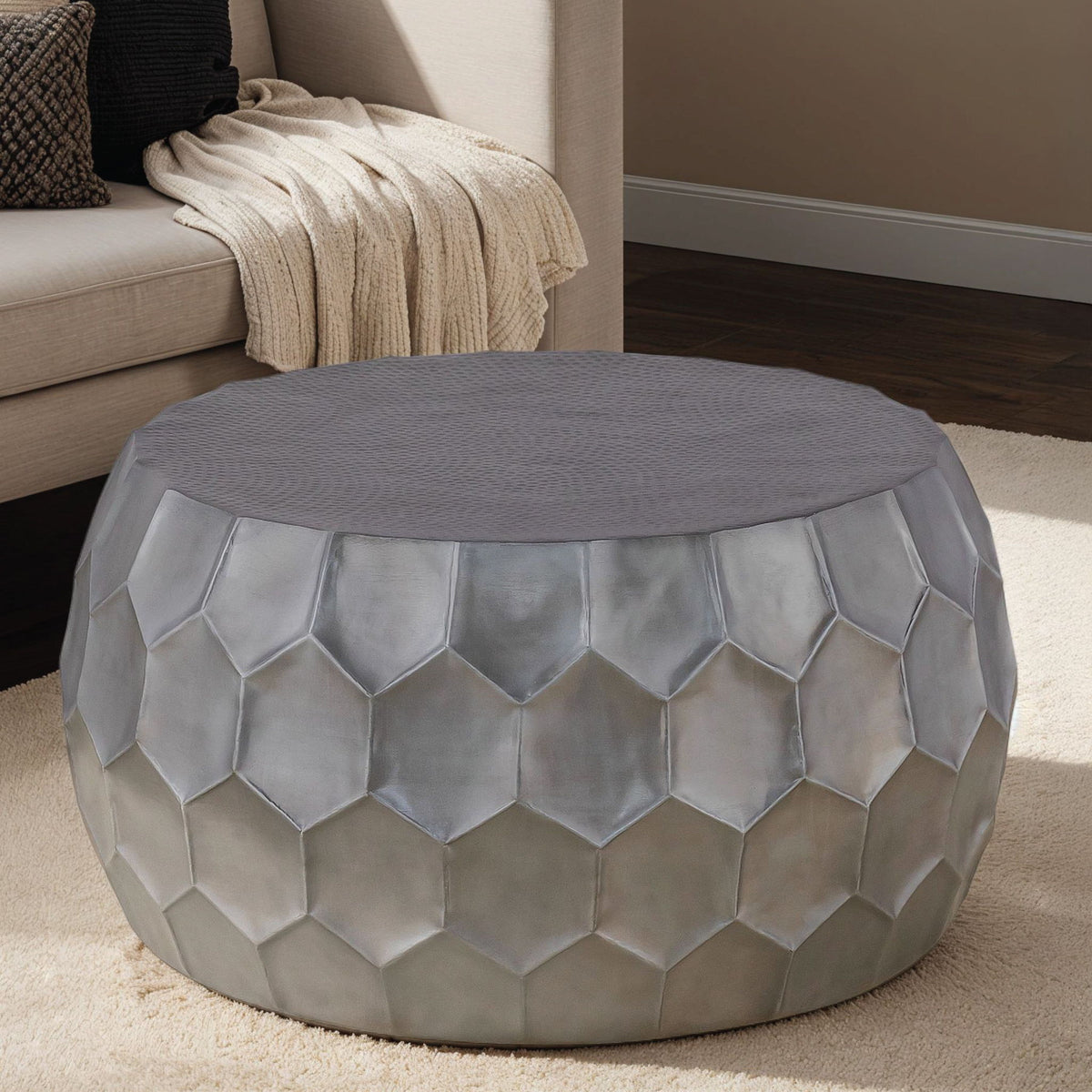 Round coffee table with pearl silver hex-pattern metal sides and gray fabric top