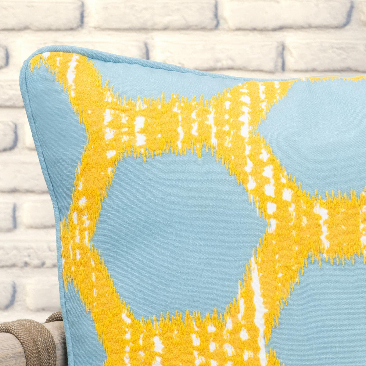 Blue pillow with yellow geometric lattice pattern and textured fringe at the corner