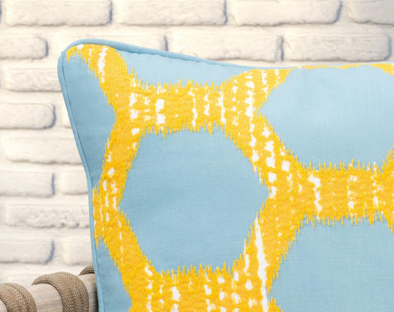 Blue pillow with yellow geometric lattice pattern and textured fringe at the corner