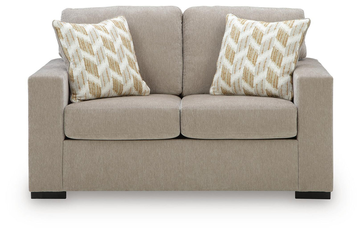 Beige loveseat with two geometric patterned pillows and divided seat cushions