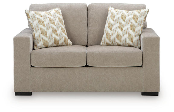 Beige loveseat with two geometric patterned pillows and divided seat cushions