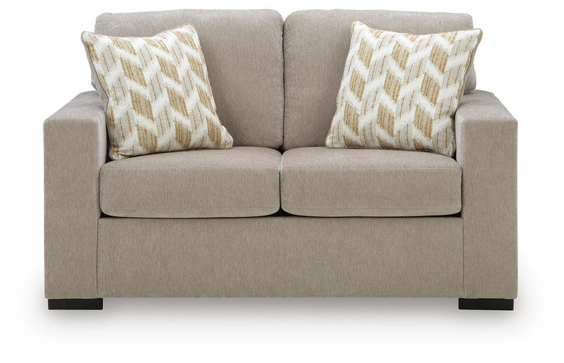 Beige loveseat with two geometric patterned pillows and divided seat cushions