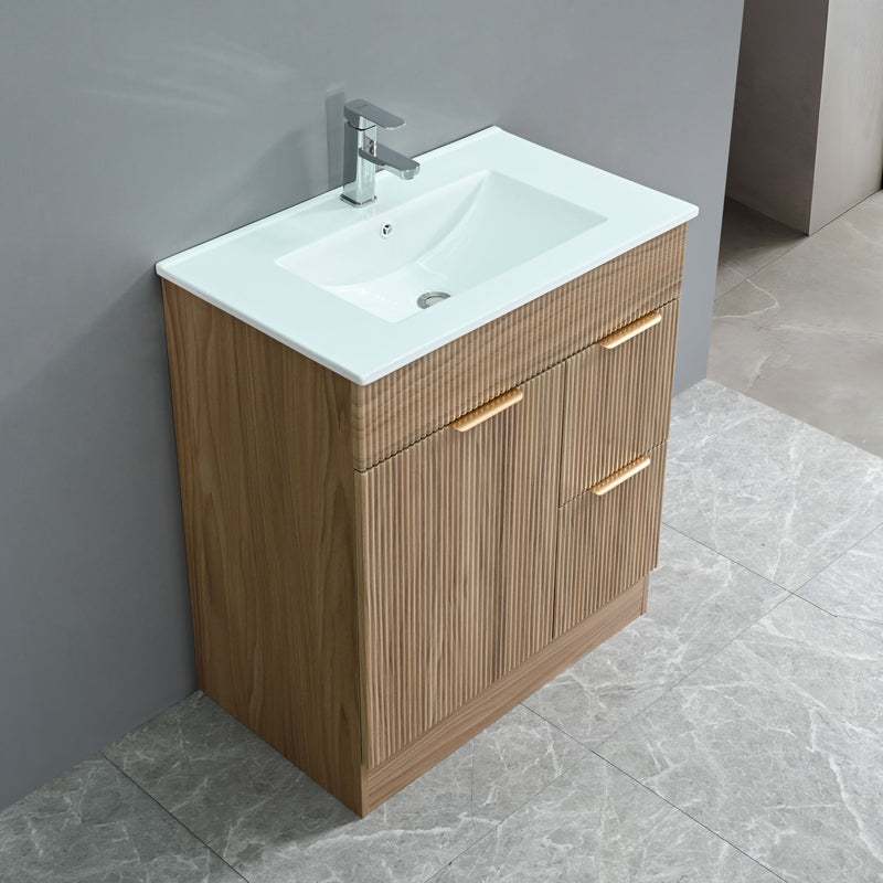 Walnut bathroom vanity with fluted drawers, cabinet door, white sink, and chrome faucet