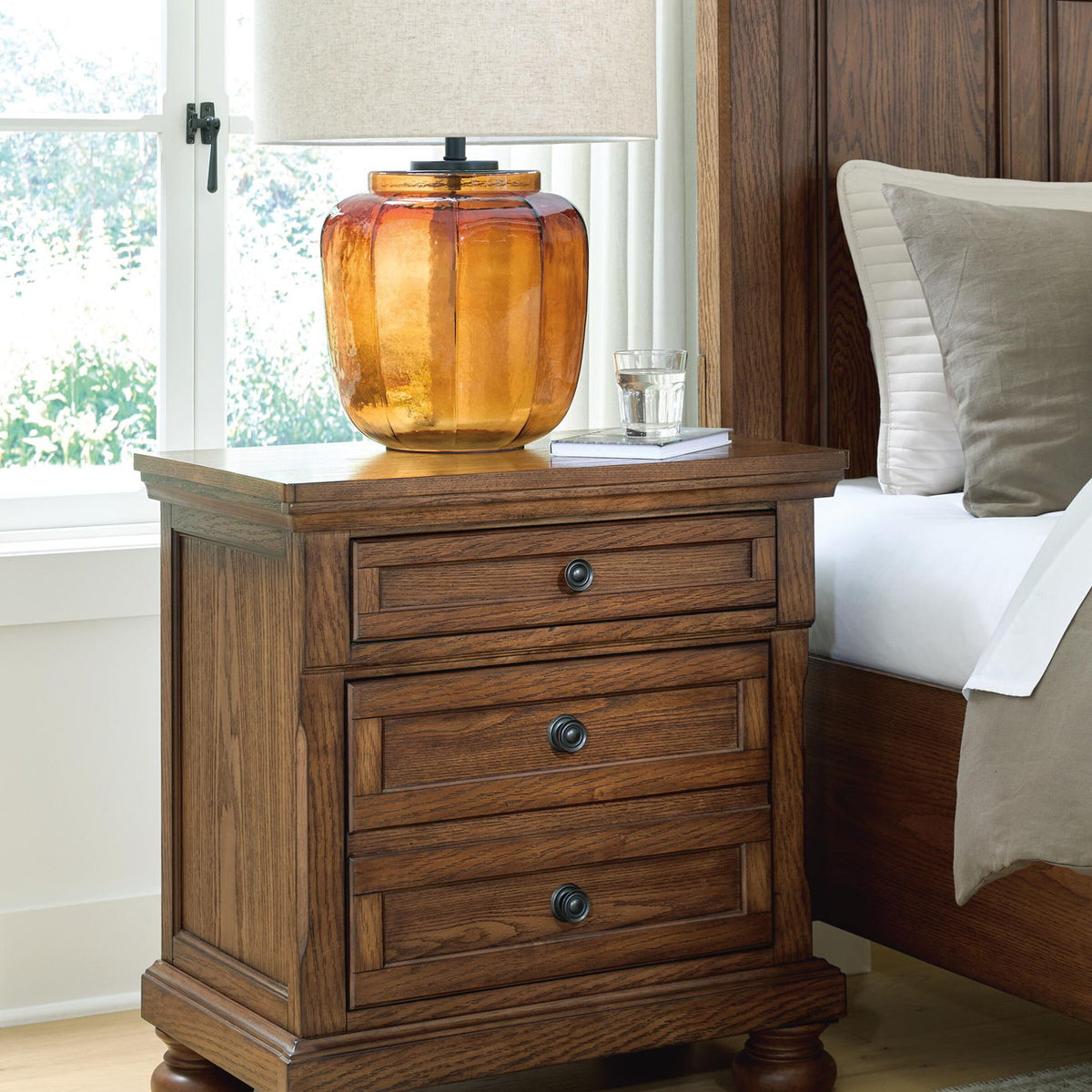 Warm brown wooden nightstand with two drawers, round metal knobs, turned legs