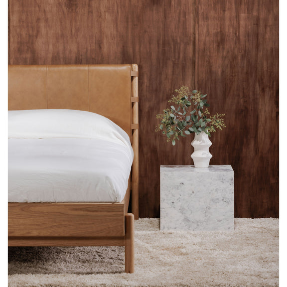 Queen bed with brown upholstered headboard, light wood frame, white comforter
