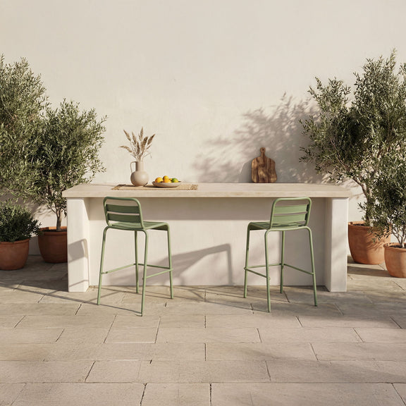Green metal outdoor bar stools with slatted backs in an outdoor patio setting