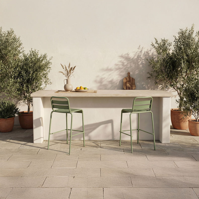Green metal outdoor bar stools with slatted backs in an outdoor patio setting