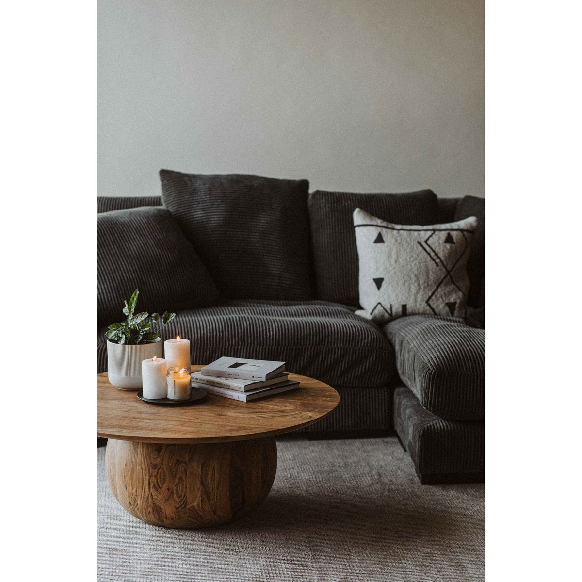 Round natural wood coffee table with carved pedestal base and circular top