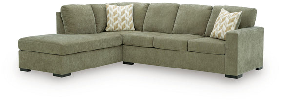Green corner chaise sectional sofa with box cushions and two patterned throw pillows.