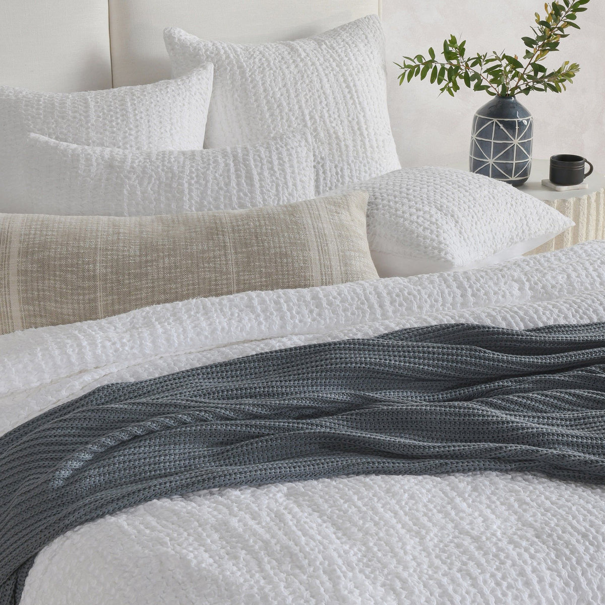 Woven sham pillow set on bed in white and dark gray, textured fabric